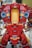 A LEGO model features a large robot or mech suit constructed from red, gold, and grey bricks. The model is detailed with sections that resemble armor plating and mechanical components, including blue translucent pieces simulating lights.