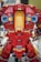 A LEGO model features a large robot or mech suit constructed from red, gold, and grey bricks. The model is detailed with sections that resemble armor plating and mechanical components, including blue translucent pieces simulating lights.