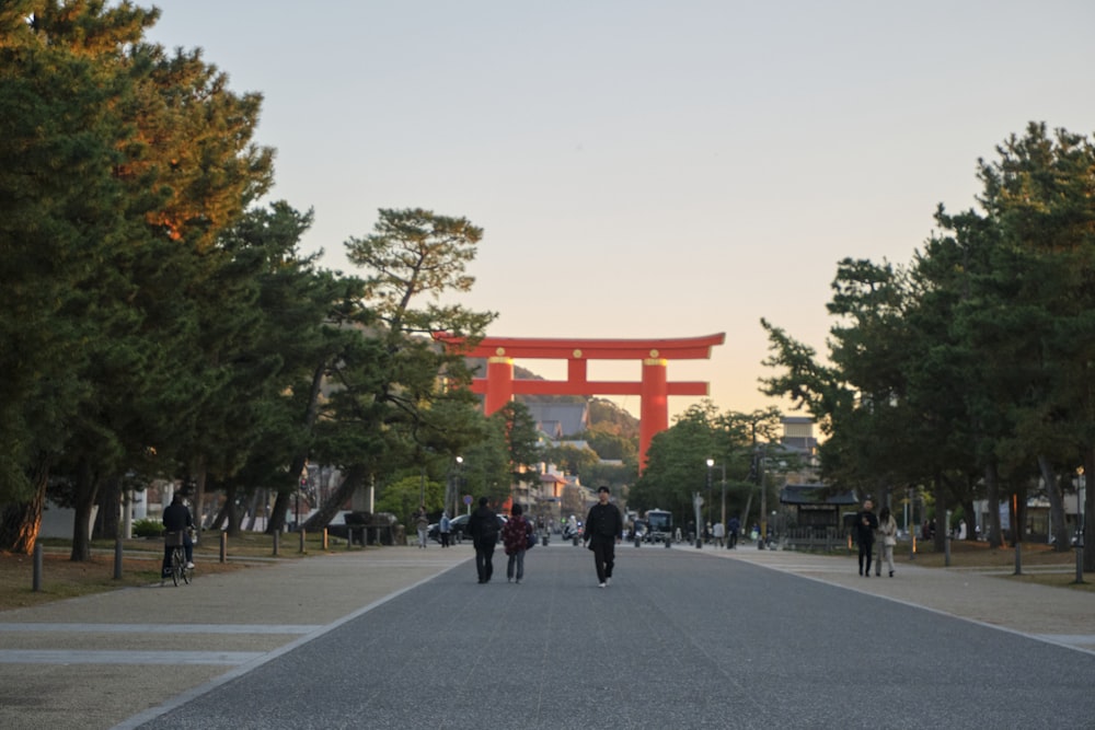a group of people walking down a street in front of a red gate