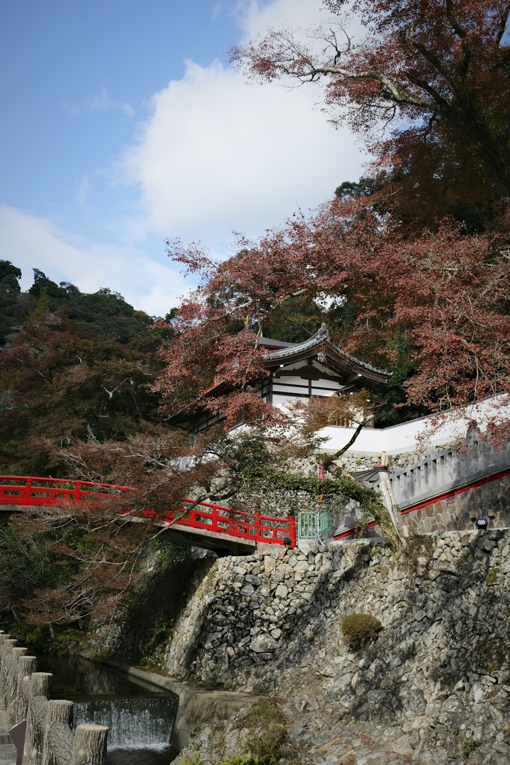 a red bridge over a small stream in a park