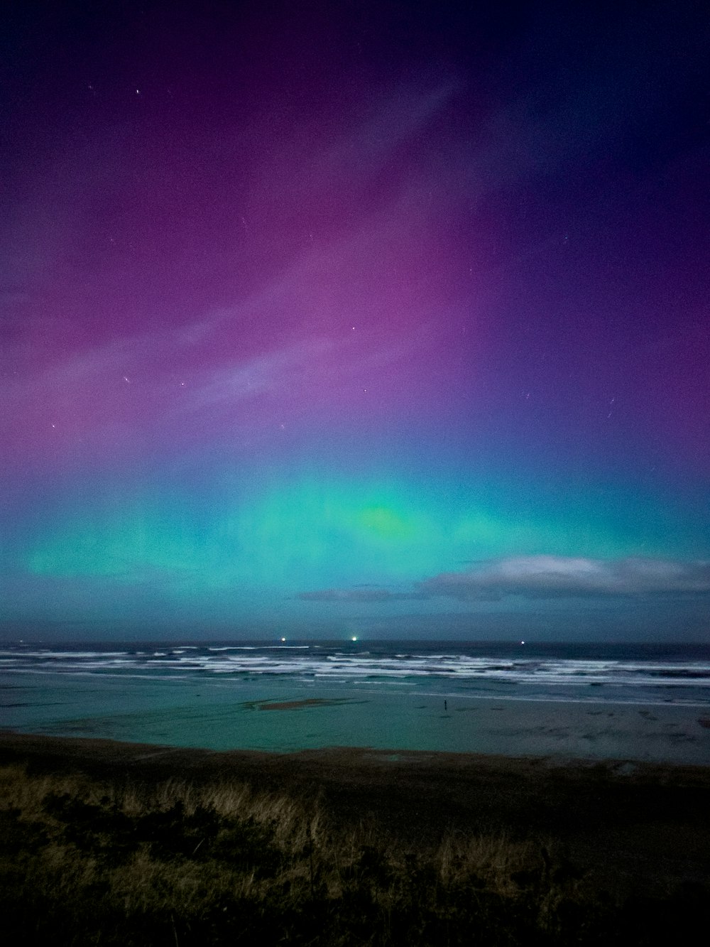 a purple and green aurora bore over a body of water
