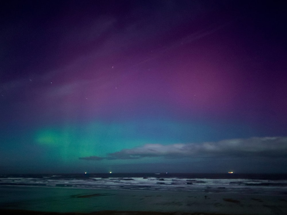 a purple and green aurora bore over the ocean