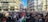 A large crowd gathered in an urban setting, holding flags and protest signs advocating for Palestinian freedom. The atmosphere is charged with activism as people stand closely together, filling the street against a backdrop of modern buildings. Many of the signs prominently display messages of support for Palestine.