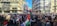 A large crowd gathered in an urban setting, holding flags and protest signs advocating for Palestinian freedom. The atmosphere is charged with activism as people stand closely together, filling the street against a backdrop of modern buildings. Many of the signs prominently display messages of support for Palestine.