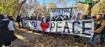 Peaceful protestors carrying banners promoting world peace in a sunny park.