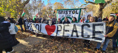 Peaceful protestors carrying banners promoting world peace in a sunny park.