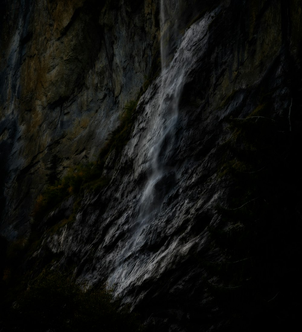 a waterfall in the middle of a dark forest