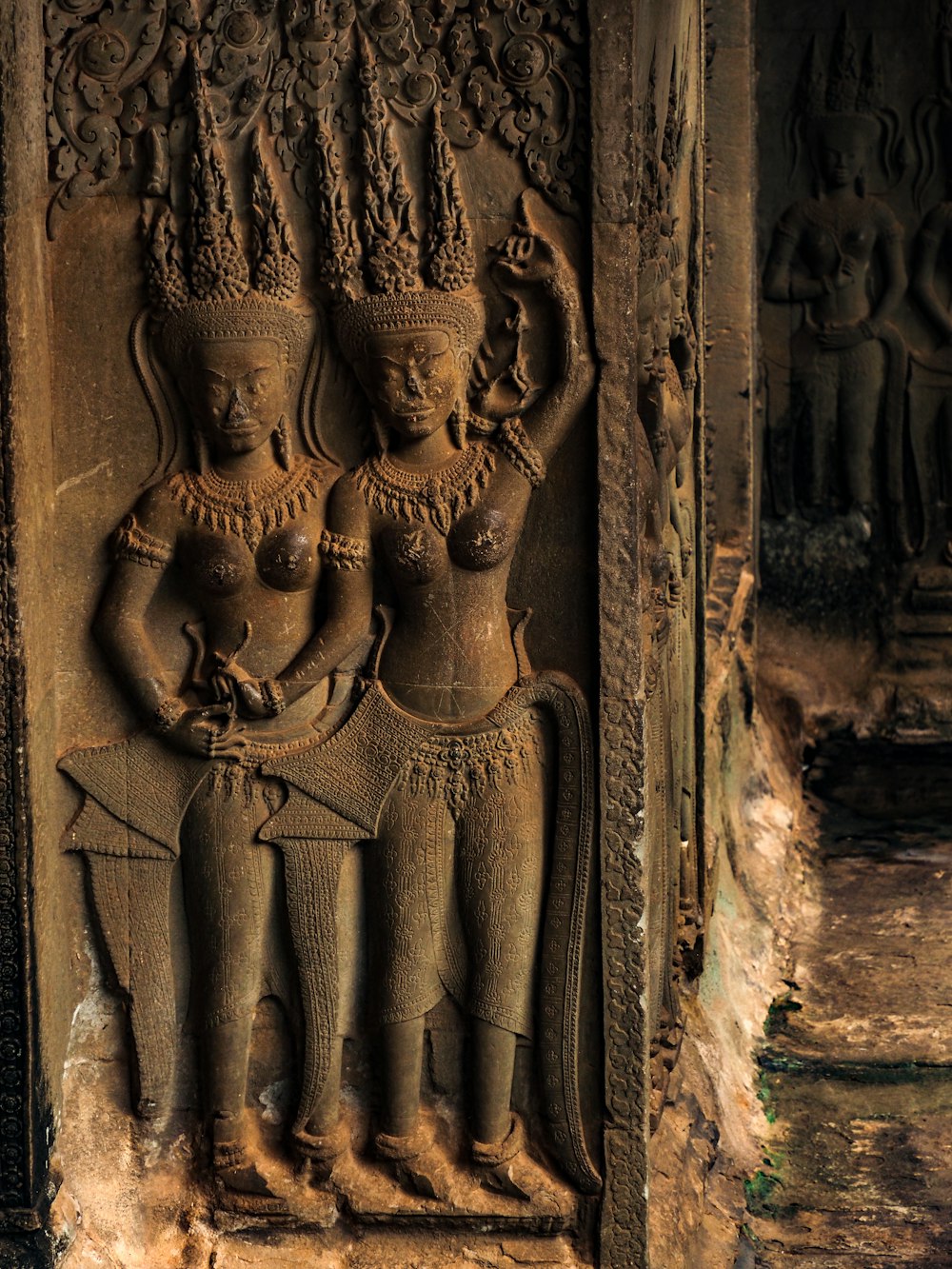 a carving of two women holding a vase