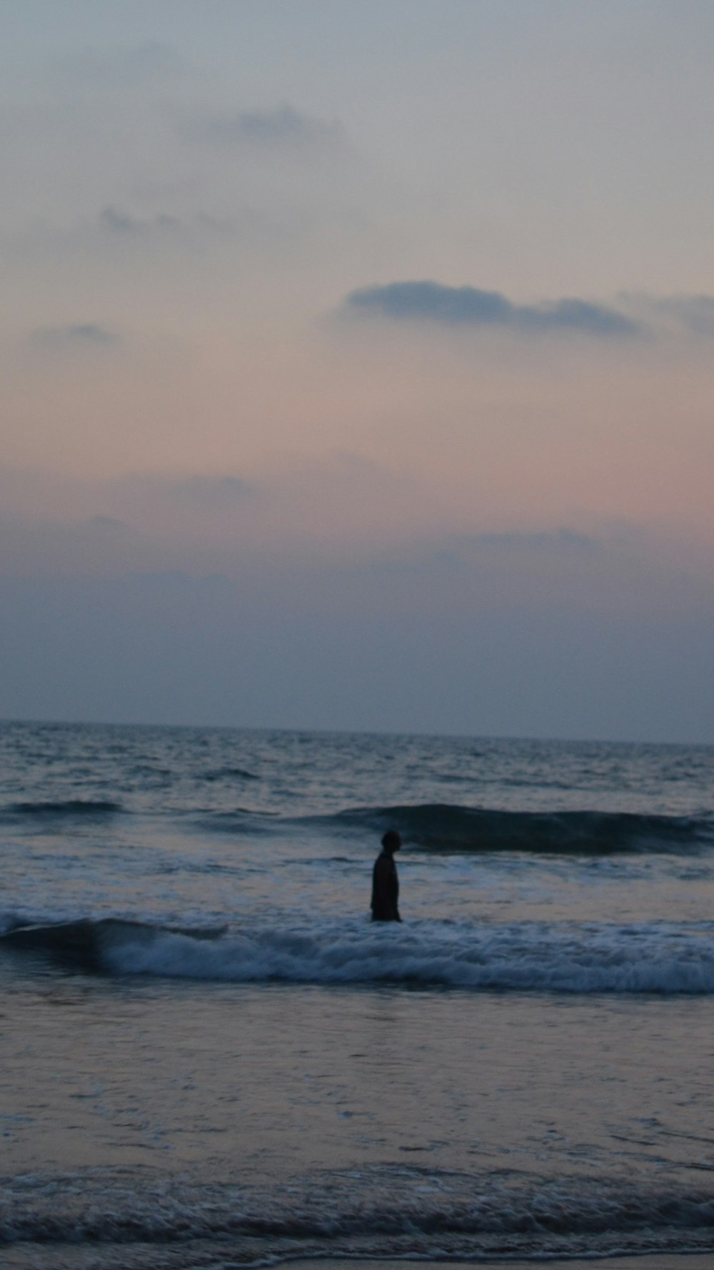 a person standing in the ocean at sunset