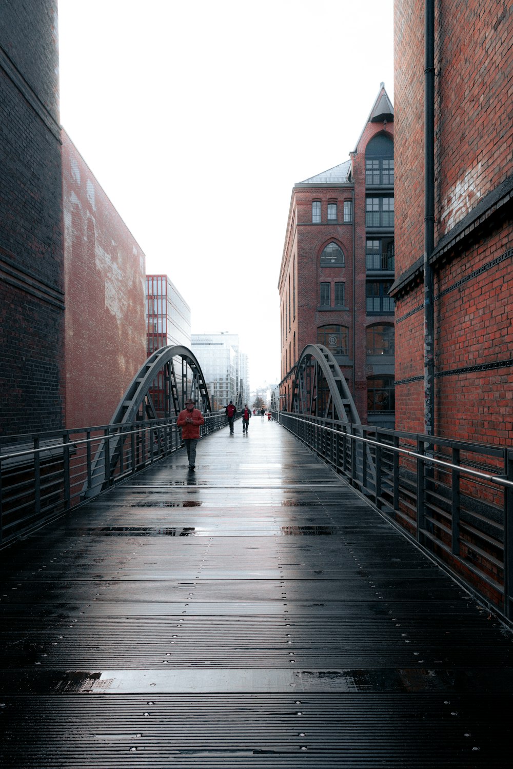 people walking across a bridge in the rain