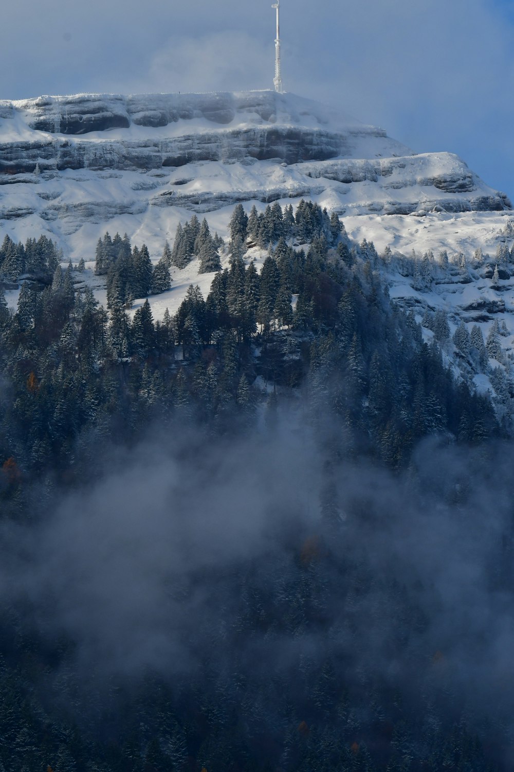 a mountain covered in snow with a radio tower on top of it