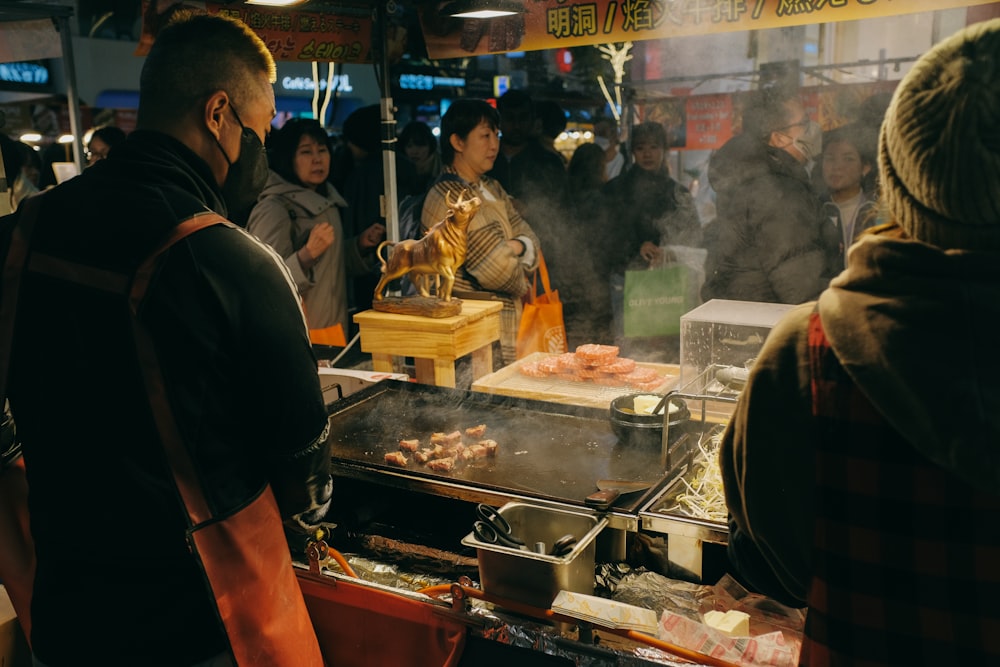 a group of people standing around a food stand