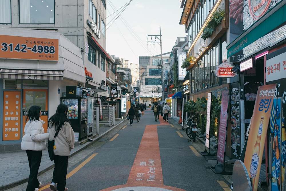 a couple of women walking down a street next to tall buildings