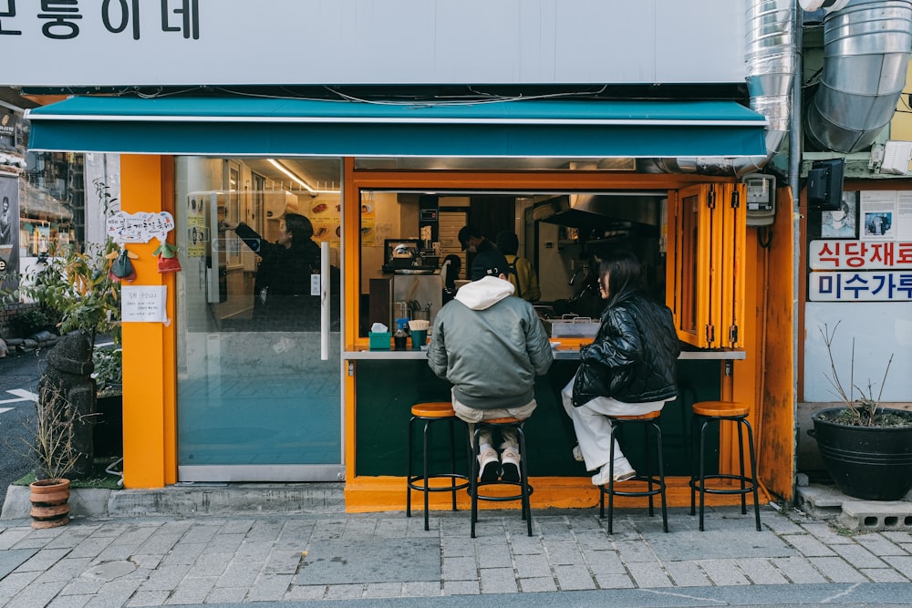 due persone sedute a un tavolo di fronte a un negozio