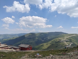 a red building sitting on the side of a lush green hillside