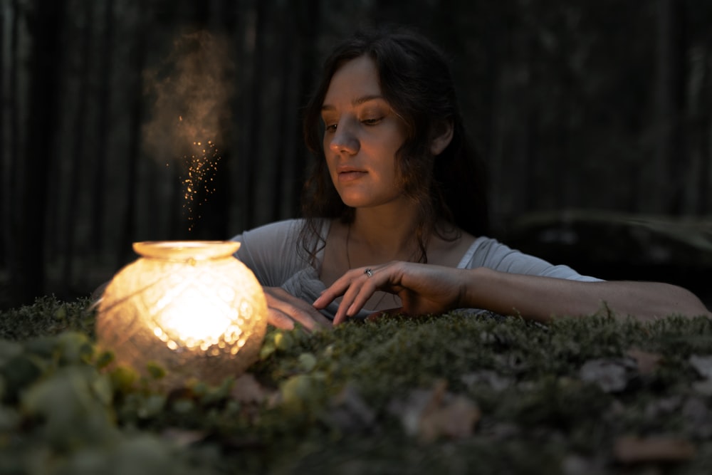 a woman sitting in the grass next to a lit candle