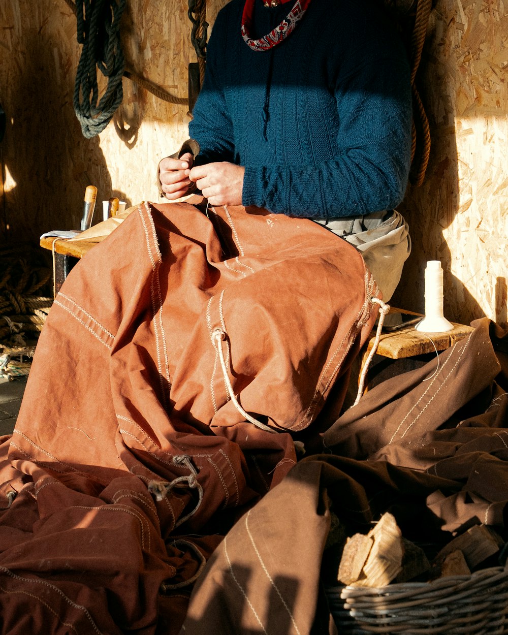 a woman sitting on the ground working on a piece of cloth