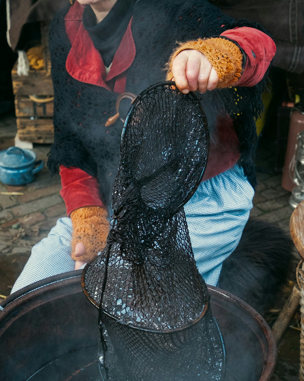 a young boy sitting on the ground holding a mesh bag