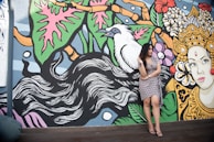 A woman twirling in a flowy dress against a colorful mural.