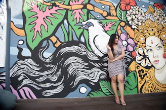 A woman twirling in a flowy dress against a colorful mural.