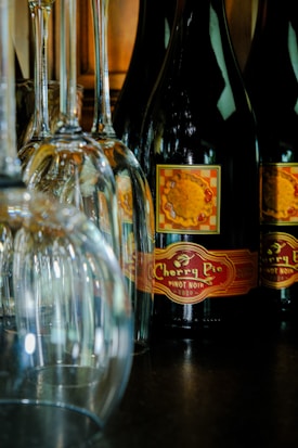 Several wine glasses are positioned alongside a bottle of Cherry Pie Pinot Noir, with a label featuring a pie image. The setup creates an elegant and inviting atmosphere.