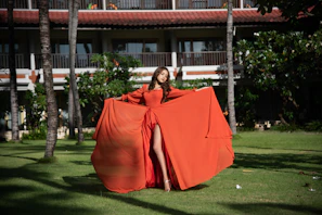A graceful woman posing in a flowing Ankara gown with geometric patterns, set in a lush garden.