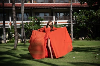 A stylish woman wearing a flowing dress in a vibrant outdoor setting.