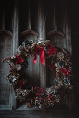 A cozy Christmas wreath decorated with pine cones and red berries hanging on a door.