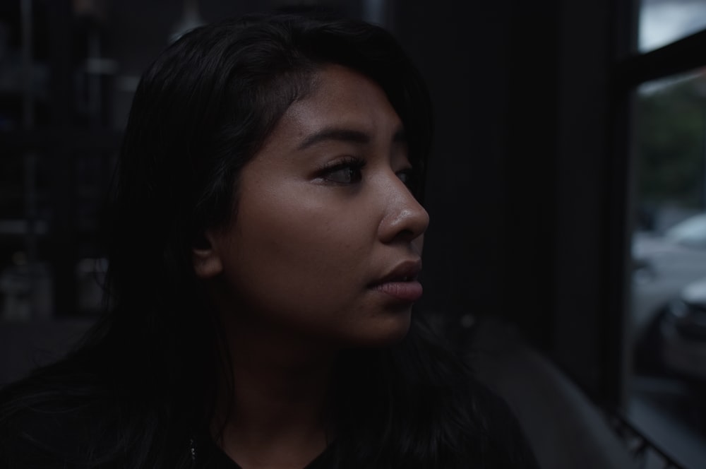 a woman looking out a window in a dark room