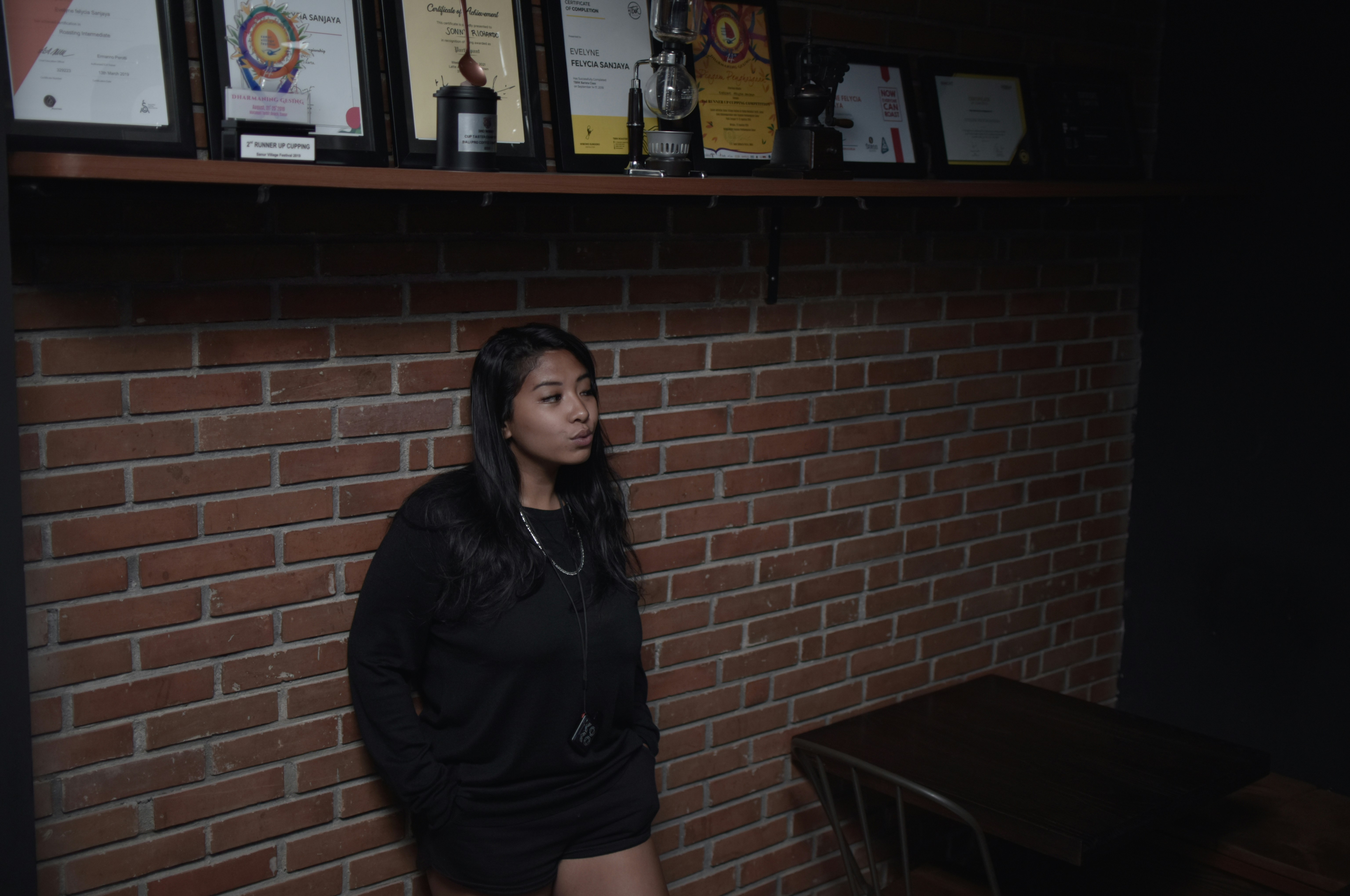 a woman standing in front of a brick wall