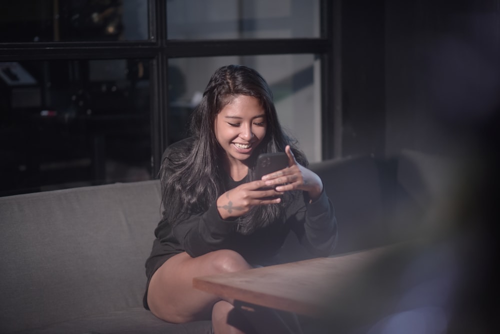 a woman sitting on a couch looking at her cell phone