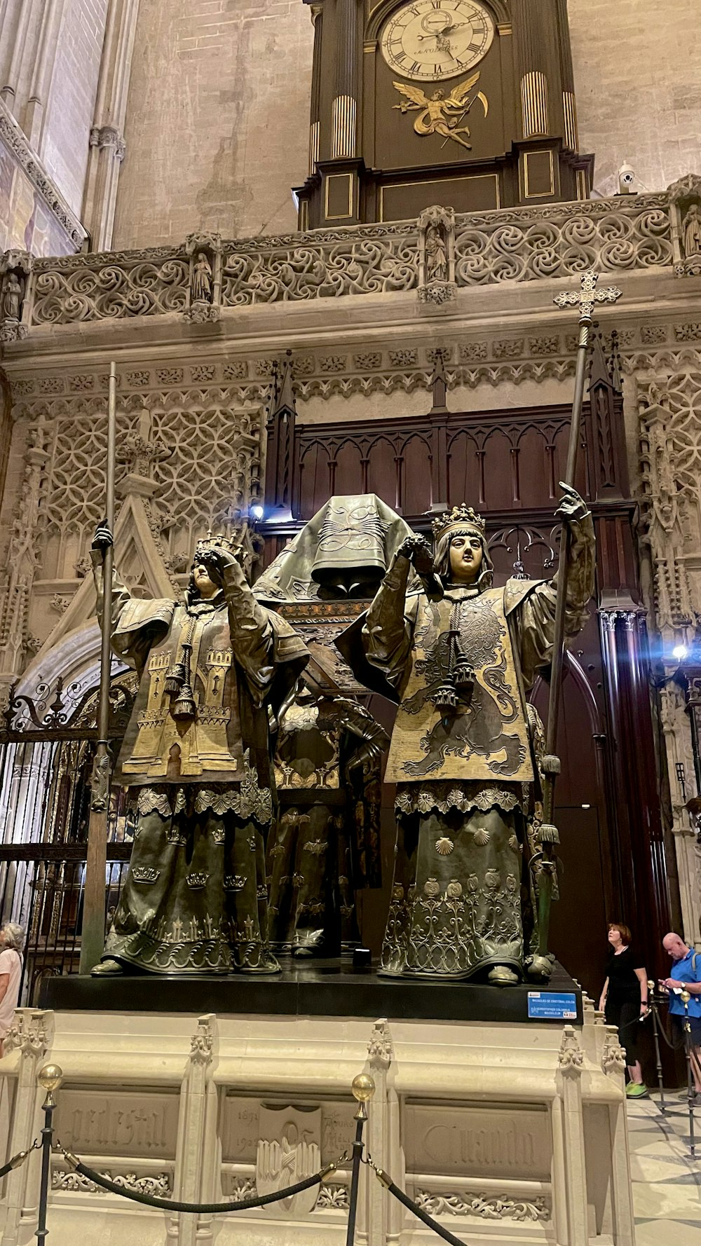 a statue of three people in front of a clock