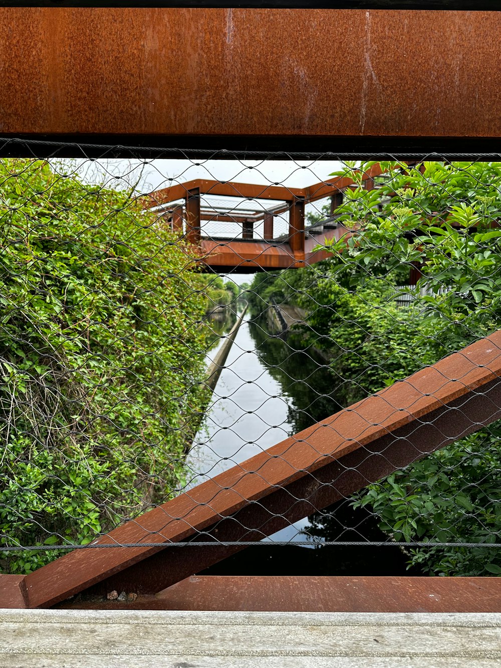 a view of a bridge over a river through a fence