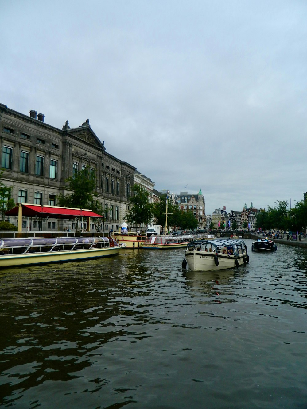 a river filled with lots of boats next to a tall building