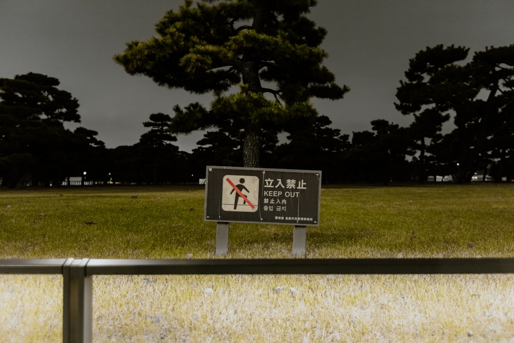 a sign that is in the grass by a fence