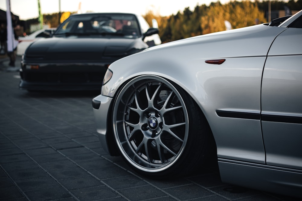 a silver car parked next to a black car