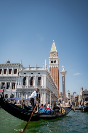 a gondola in a canal with a tall building in the background