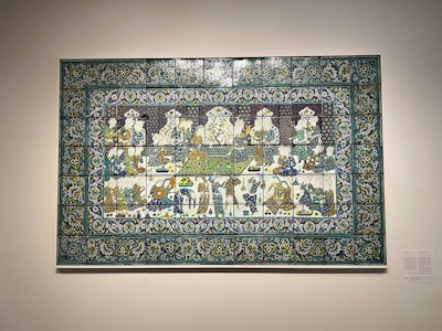 Intricate dombormű plaque depicting a story scene on a warm beige background.