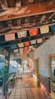 Sunlit hallway decorated with colorful papel picado banners and rustic wooden doors.