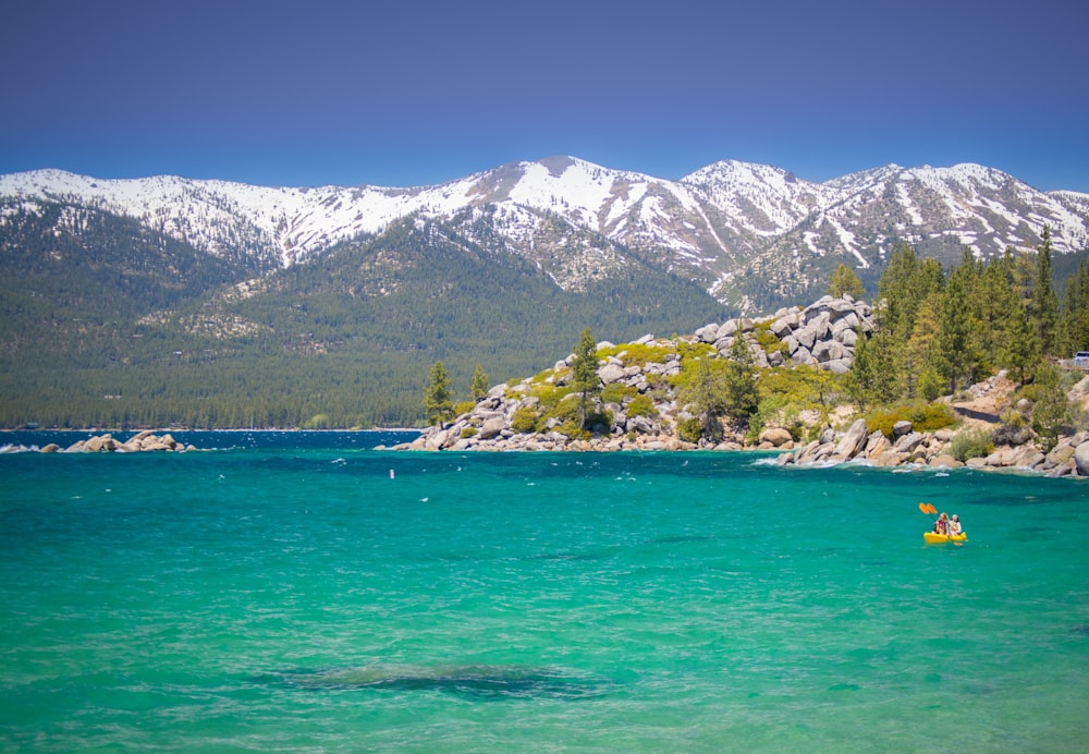 a person in a kayak in a lake with mountains in the background