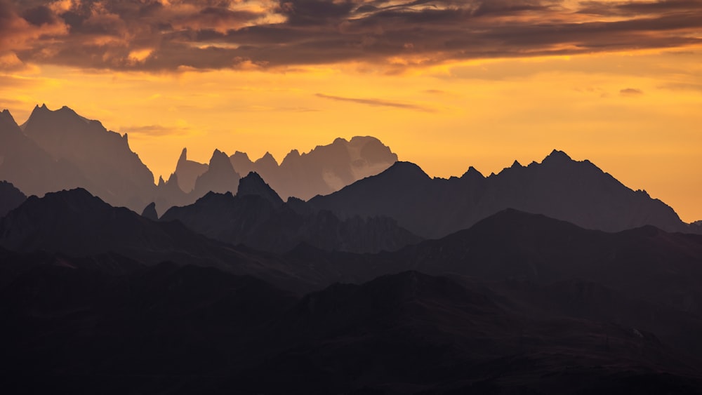 the sun is setting over a mountain range