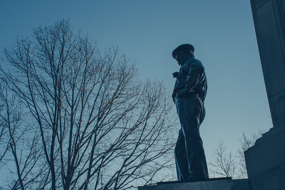 a statue of a man standing next to a tree