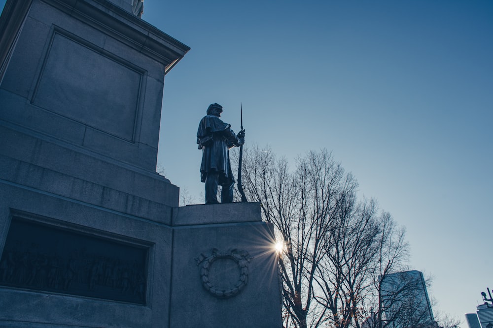 una estatua de un hombre sosteniendo un rifle en la parte superior de un edificio