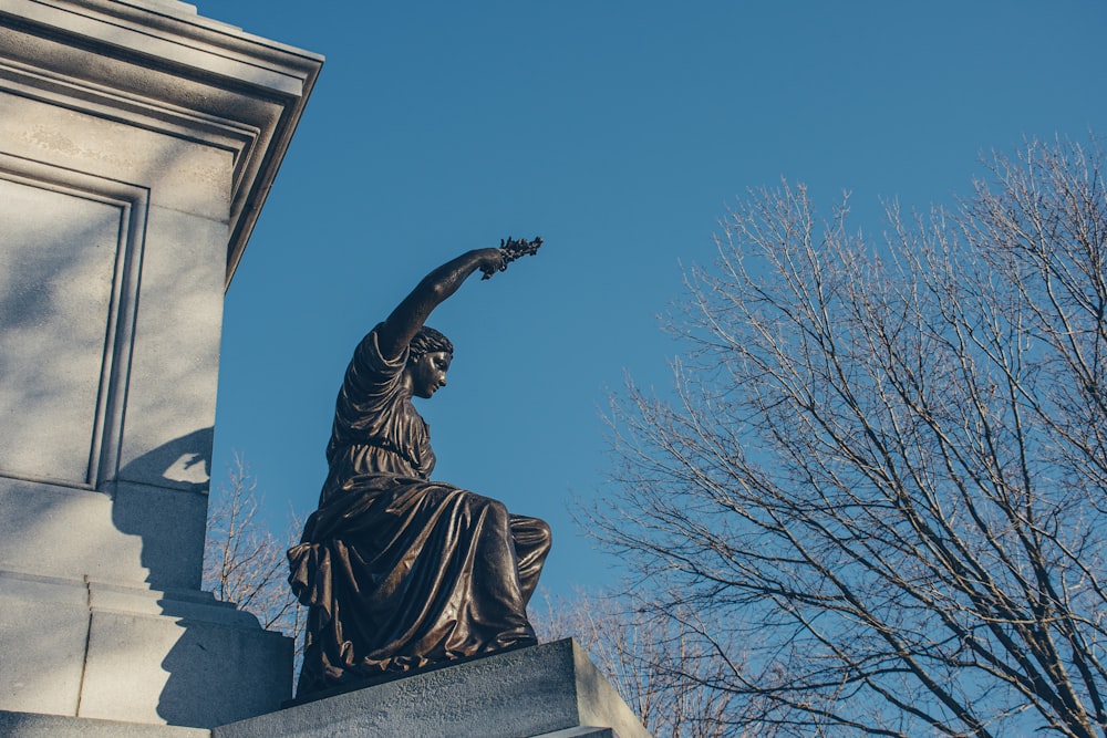 a statue of a woman holding a flower in her hand