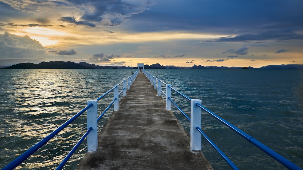 a long pier extending into the ocean under a cloudy sky