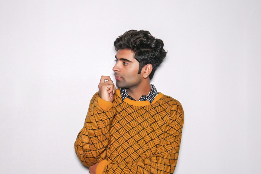 a man in a yellow sweater posing for a picture