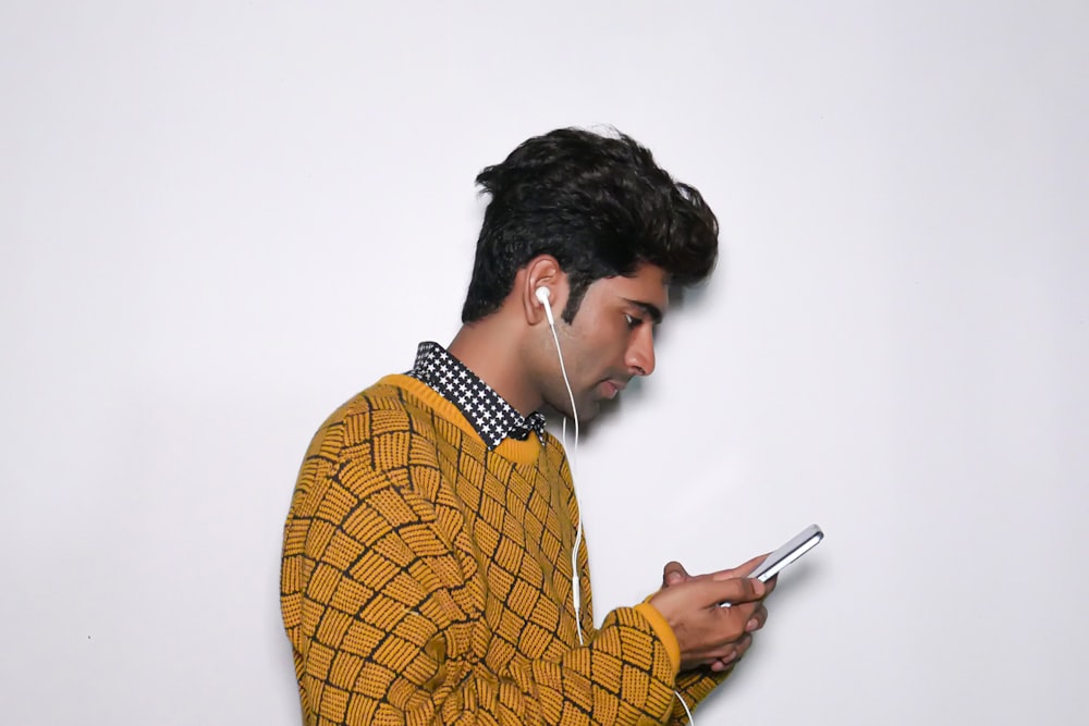 a man wearing headphones looking at his cell phone