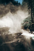 Sunset light illuminating a misty waterfall surrounded by dense forest.