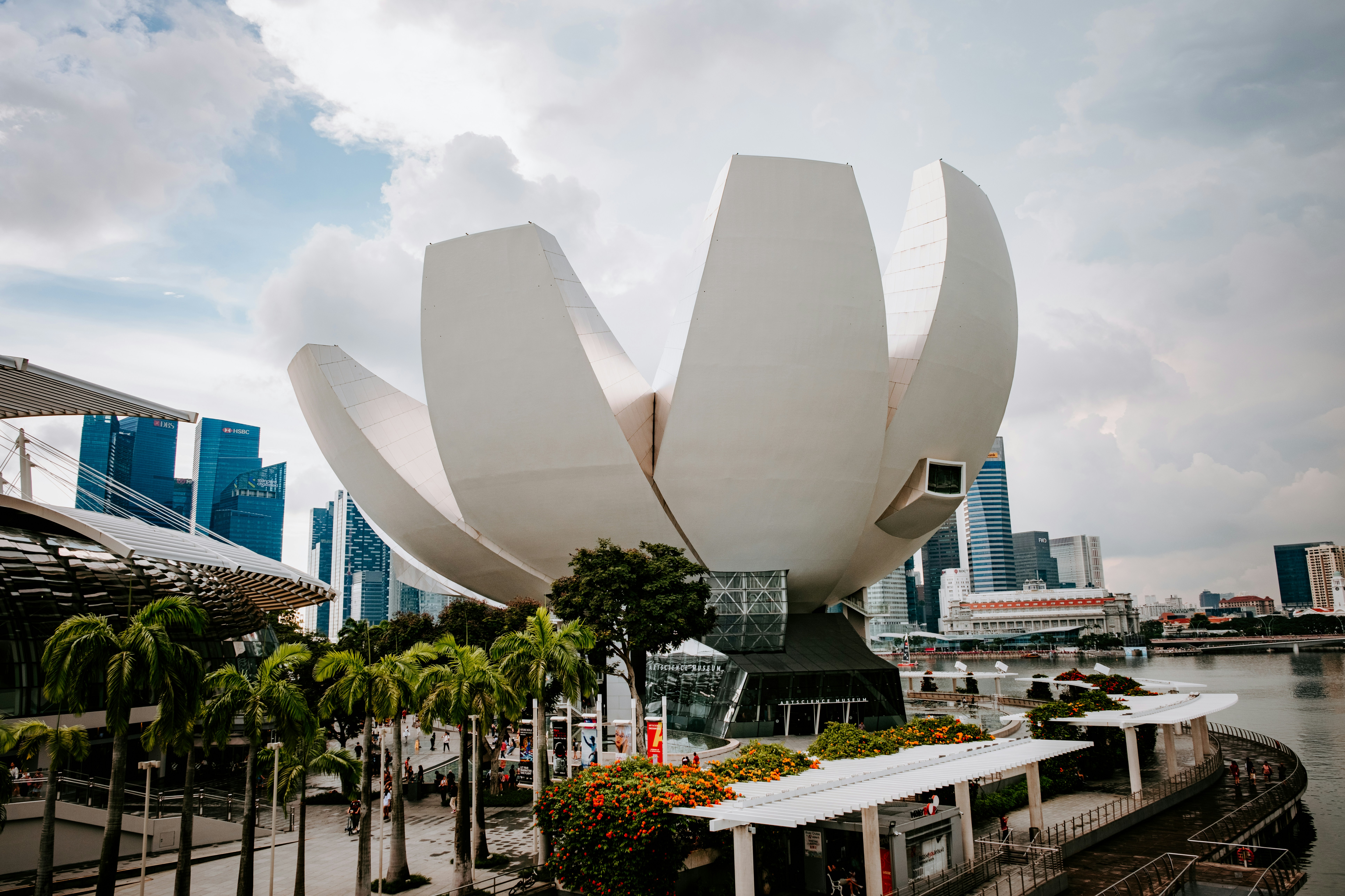 a large white flower sculpture in front of a body of water