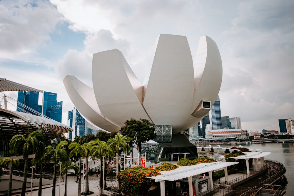 a large white flower sculpture in front of a body of water